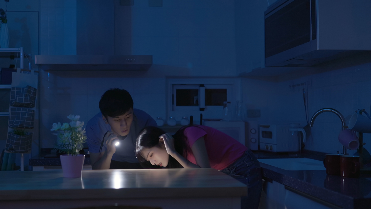 A man and a woman looking at a light in a kitchen