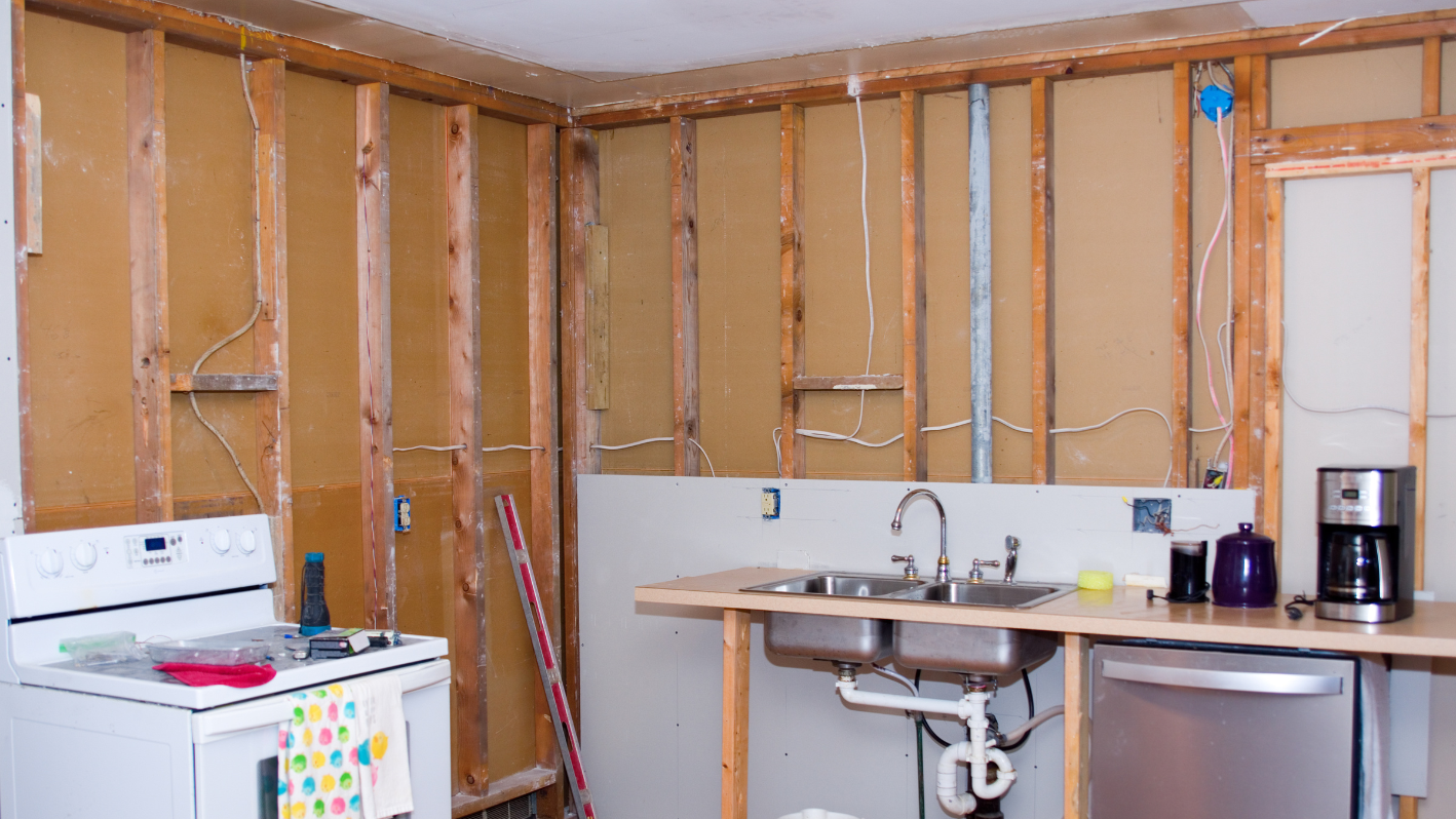 A kitchen under construction with a sink and refrigerator