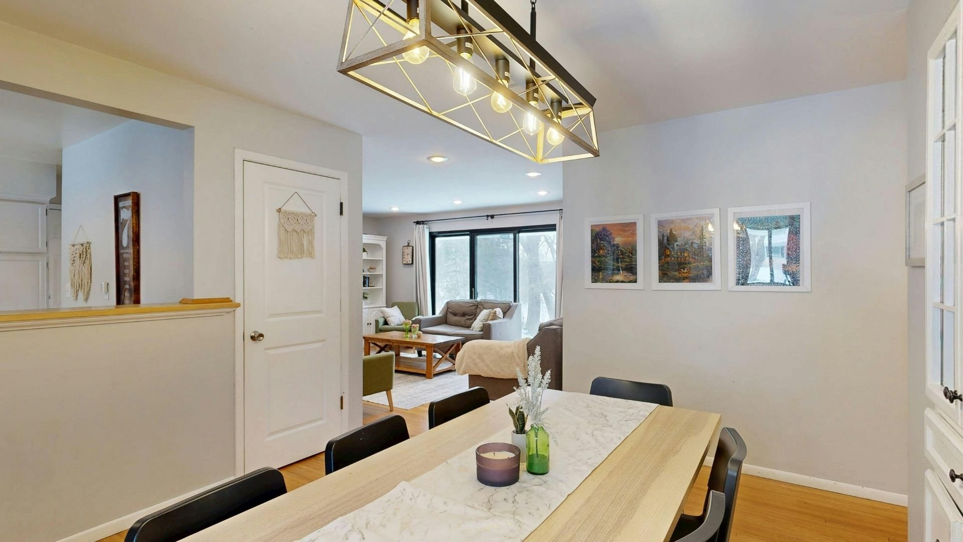 Modern dining room with marble table, geometric pendant light, and open living space beyond