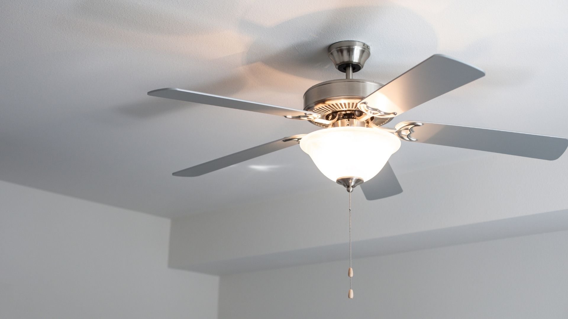 Brushed nickel ceiling fan with four blades and integrated light fixture.