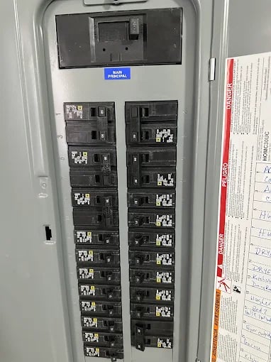 Electrical panel with multiple black circuit breakers and digital display on top