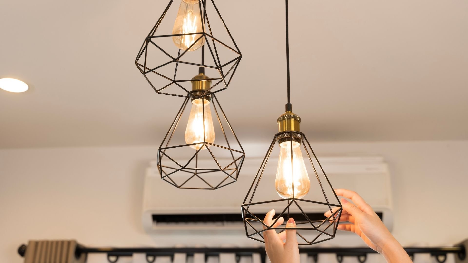 Geometric pendant lights with Edison bulbs hang from ceiling in modern interior